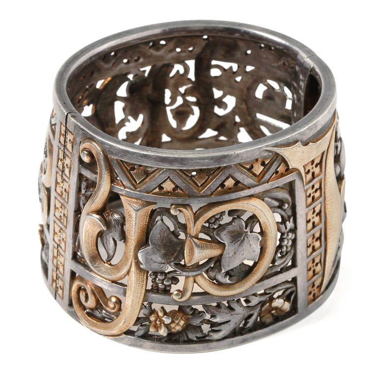 An important silver and vermeil neo gothic cuff bracelet, delicately engraved and repierced with floral patterns, grapes, and the name Jehanne for Joan of Arc, signed on the edge: Couquaux, 1885. Couquaux's work is characteristic of the esthetical