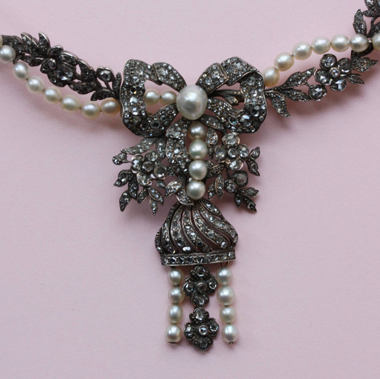 A romantic flower garland necklace with a pendant of a bow, flowers and a tassel, all with the most beautiful grey rose cut diamonds interspersed with natural pearls, engraved gilt backing, Dutch, circa 1850. with original box retailed by J.A.