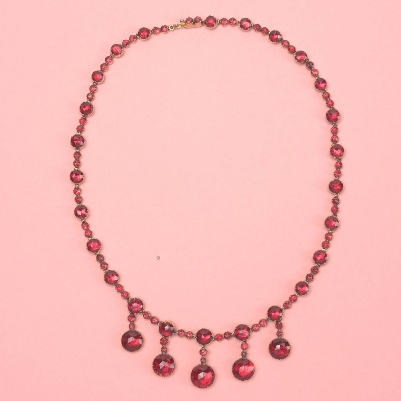 An 18 carat gold necklace with rose cut rhodolite garnets set on red pinkish gold foil. Five larger rose cut garnets suspend from the necklace, South of France, 19th century.

weight: 27.3 grams
length: 40 cm.