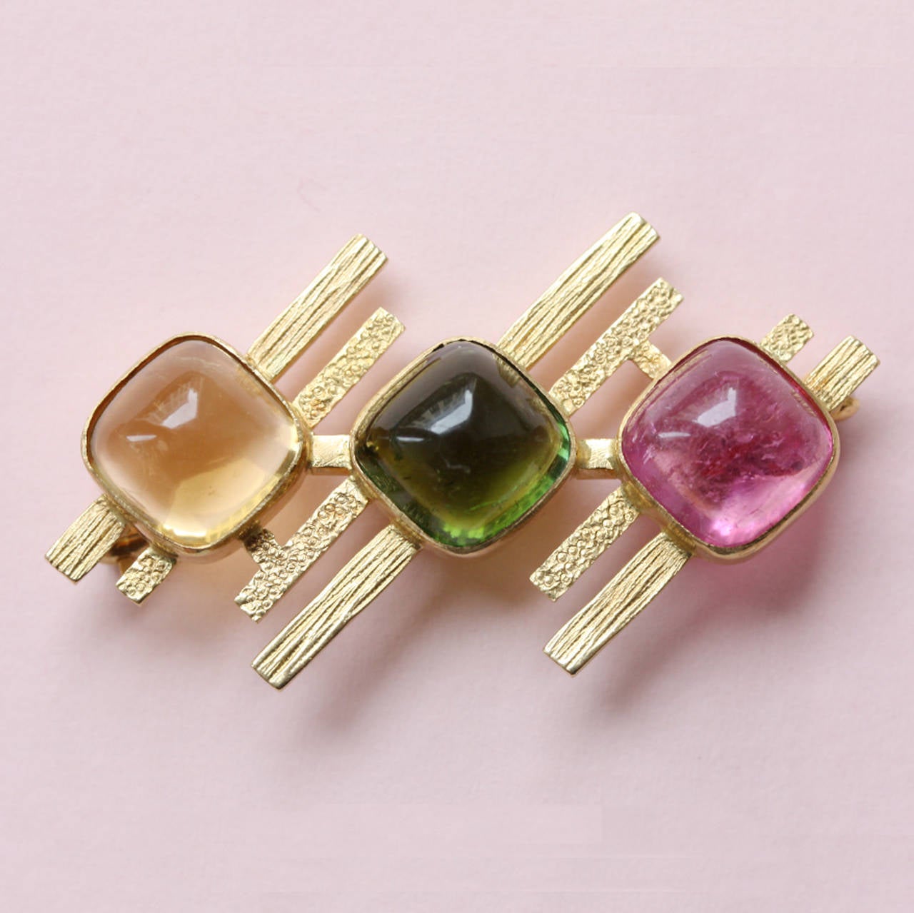 An 18 carat gold geometrical brooch set with a pink and green tourmaline and a citrine all in sugarloaf cut, signed: MK(J)LTD. Chester. circa 1968-1977.

weight: 11.3 gram
dimensions: 4.6 x 2. cm.