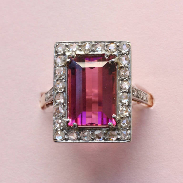 A rectangular gold ring set with a bright pink tourmaline surrounded by small rose cut diamonds set in platinum (app. 0.6 carats), circa 1910.

weight: 4.3 grams
ring size: 17.75 mm. 7 ½ US.