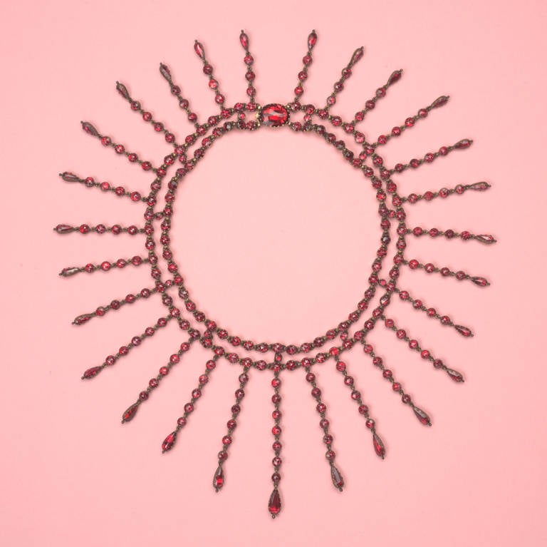 An 18 carat gold choker fringe necklace set with rose cut rhodolite garnets on red gold foil.  Perpignan, France, circa 1890. 

length: 34 cm.
length shortest fringe: 6.5 cm.
lengte longest fringe: 3 cm.
weight: 71 grams