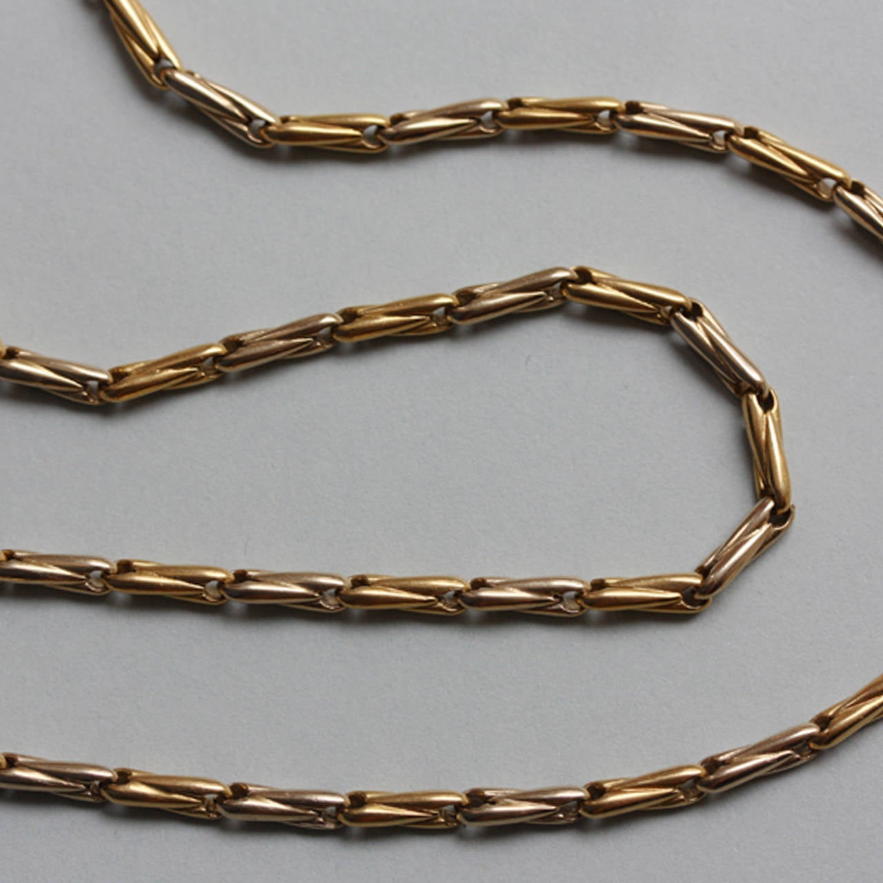 A two colored 18 carat gold chain with a grain link, signed and numbered: Cartier, circa 1970.

weight: 30 grams
length: 46 cm.