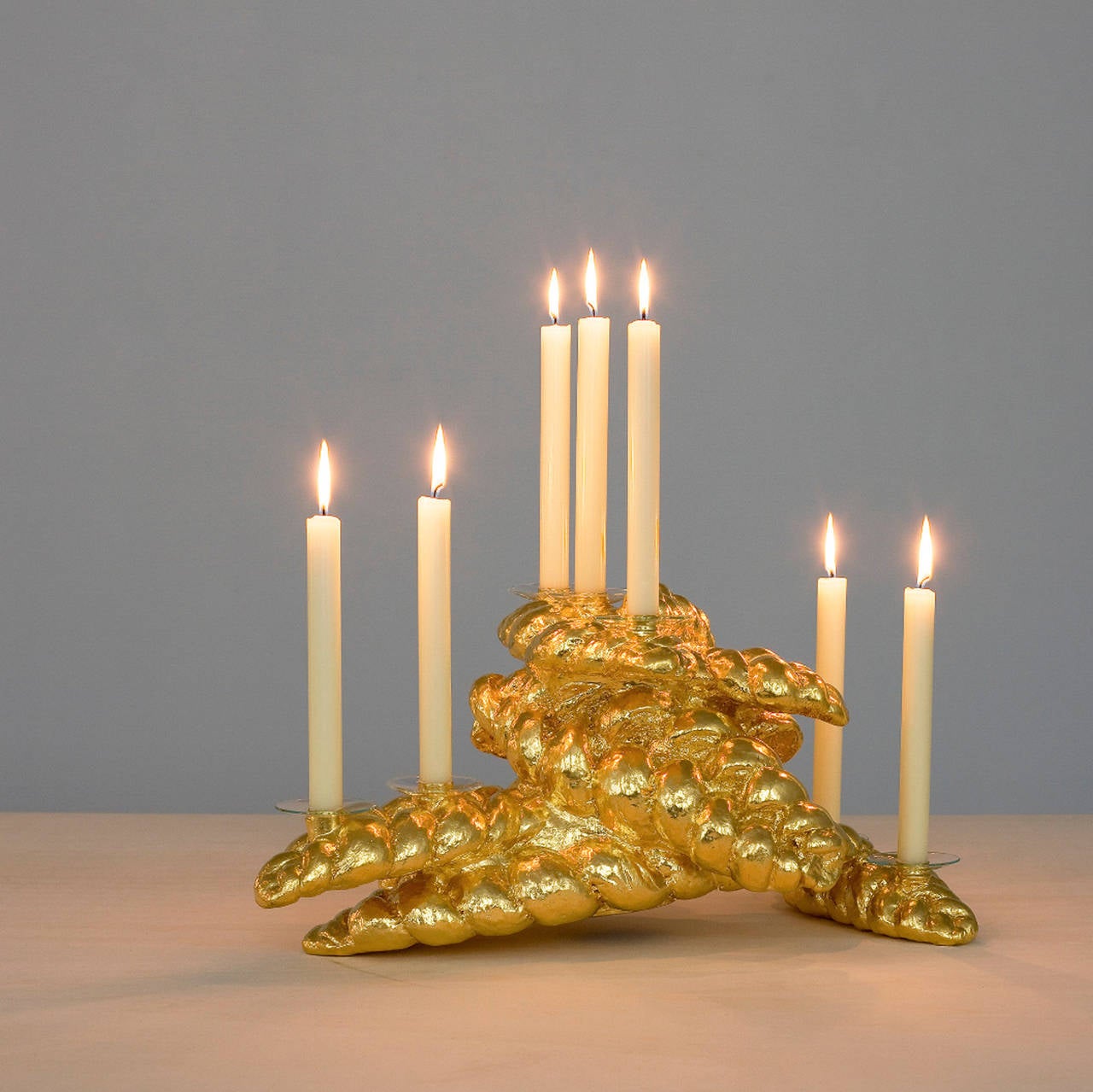 Manna, Nr. 2/5, ist ein Leuchter, der aus 7 verschiedenen geflochtenen Broten (Challah) besteht, die in Aluminium gegossen und mit 23,75 Karat Gold vergoldet sind, in der Serie Sonne - Weizen - Gold.

 abmessungen: 24,5 x 53 x 33 cm.

Kees de
