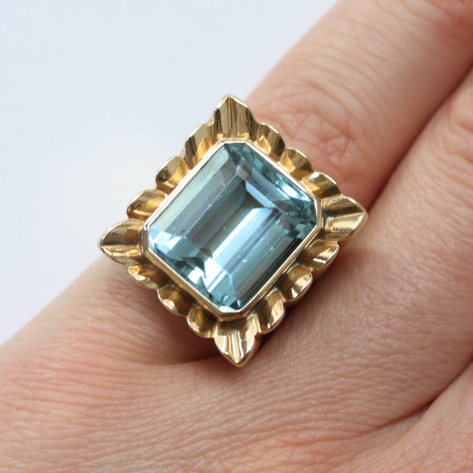 An 18 carat gold reactangular ring set with a large emerald cut aquamarine and a striped gold shank, French master mark, France, circa 1950.

weight: 14.5 grams
ring size; 16 mm. 5 1/4 US.
dimensions 1.9 x 1.8 cm.