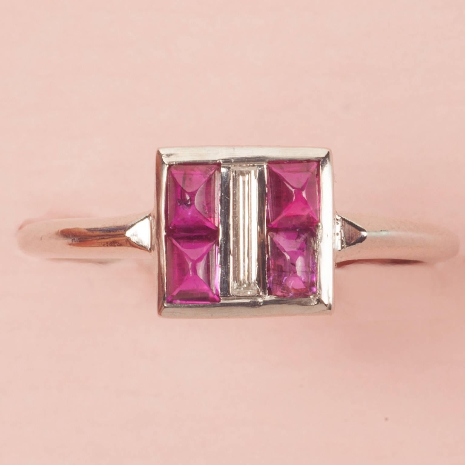 A platinum Art Deco ring. Set with four square sugarloaf- cut rubies centered around a  small baguette cut diamond (app. 0.1 carat). Circa 1920. US.

ring size: 17 mm. 6 ½ US
weight: 3.9 gram
dimensions : 7 x 7 mm. 