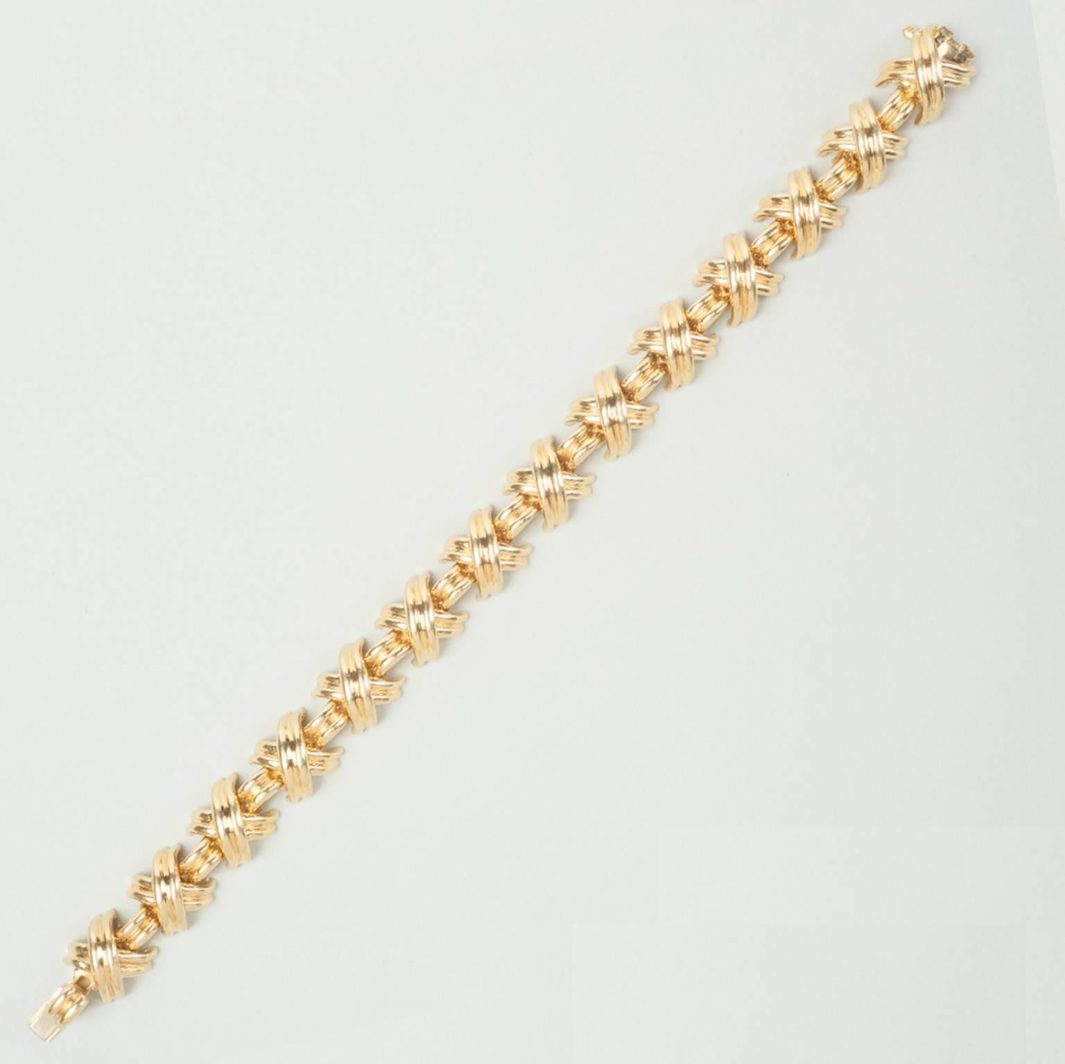 A classic 'Kisses' bracelet, designed with a series of grooved 'Kisses' links, interspaced by grooved links, to the push-piece clasp. Signed Tiffany & Co. 750.

weight: 47.9 grams
length: 18.5 cm.
width: 1.1 cm