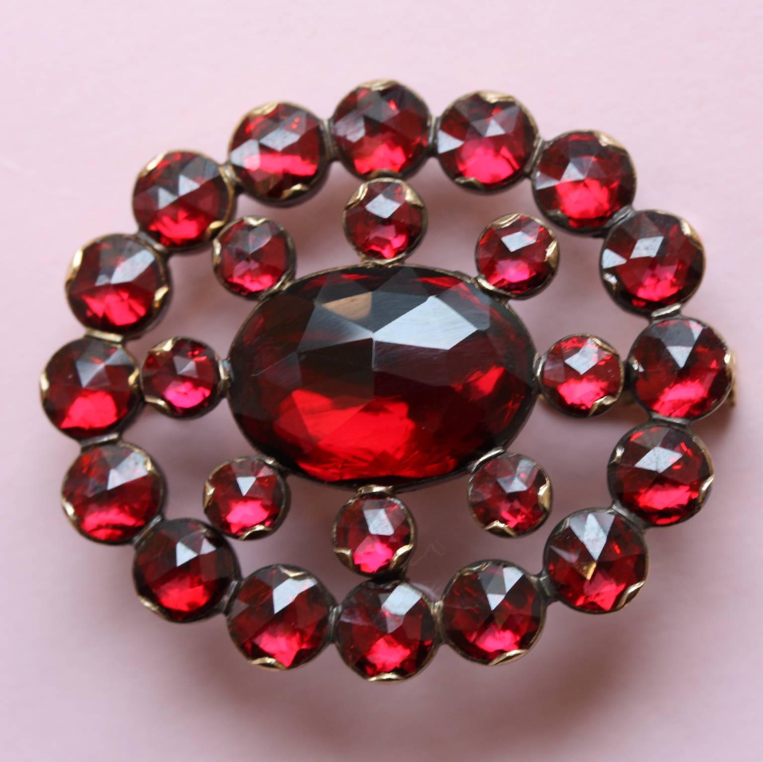 An oval 18 carat gold brooch set with one oval and 24 round rose cut deep red and sparkly rhodolite garnets, South of France, 19th century.

weight: 5.9 grams
dimensions: 4.4 x 3 cm.