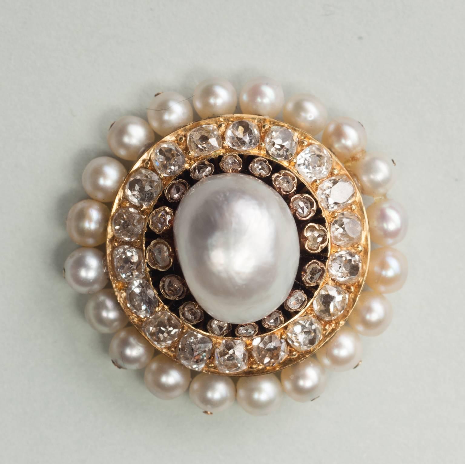 A round brooch or pendant set with a large natural pearl (app. 5 carats) around with a border of small rose cut diamonds around which a border of 18 old cut diamonds (app. 2 carats) and on the outside border 20 round and button shaped pearls, 19th