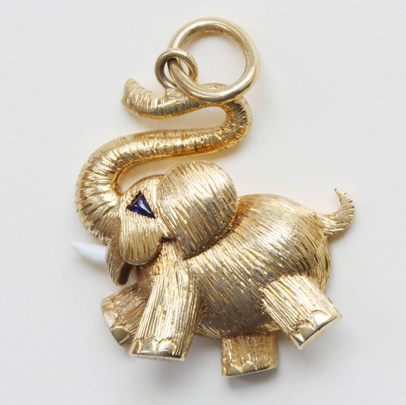 An English 18 carat gold happy elephant luck charm. His trunk is up and his eye is made with a triangle cut sapphire, his tusk is made of bone, finely engraved. The elephant is signed and numbered: Cartier, London, 1975.

weight: 13.2