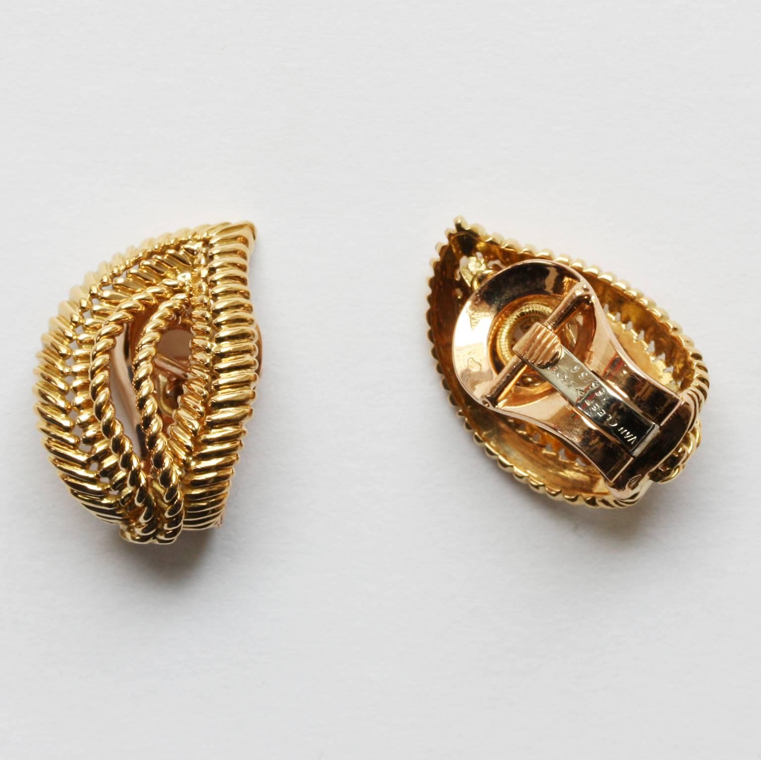 A pair of 18 carat gold ear clips (convertable to dress clips) in the shape of stylized leaves, signed and numbered: Van Cleef & Arpels, 66156, circa 1950, France.

weight: 12.8 grams
dimensions: 2.3 x 1.6 cm.