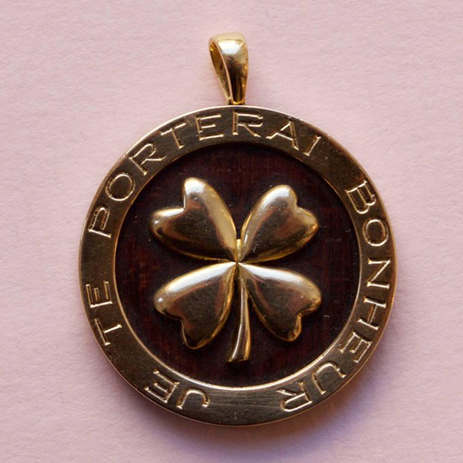 An 18 carat gold and bois d'amourette pendant with a clover and the text 'Je Te Porterai Bonheur' (I will bring you luck) signed and numbered: Van Cleef & Arpels, B1298 B58, France.

weight: 8.2 grams
dimensions: 3.5 x 2.7 cm