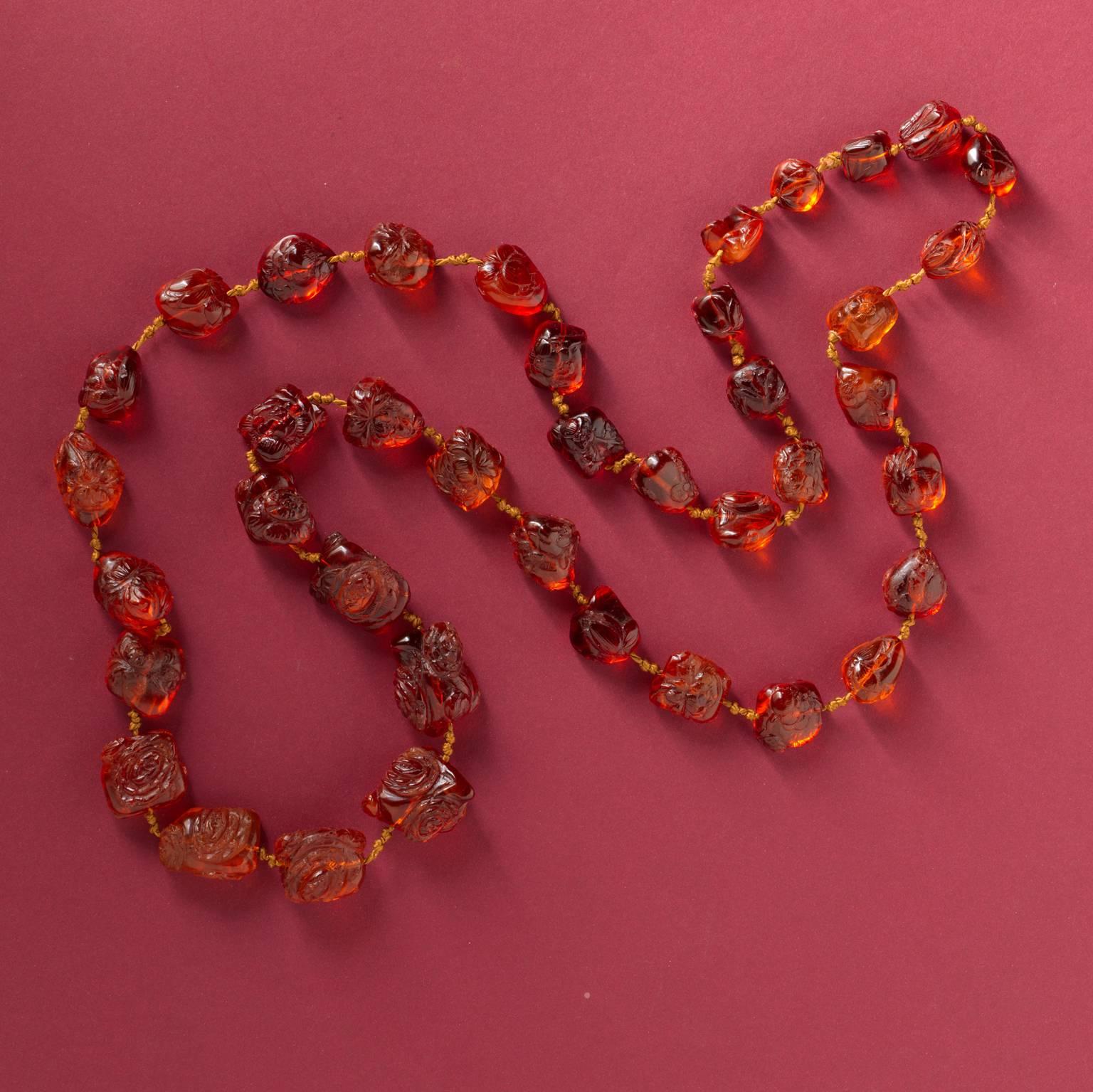 An important necklace composed of 40 graduating amber beads carved with floral motifs, the beads measure approximately 27 x 14 mm to 14 x 14 mm, strung on silk, Chinese, 18th century.

weight: 197 grams
length: 136 cm