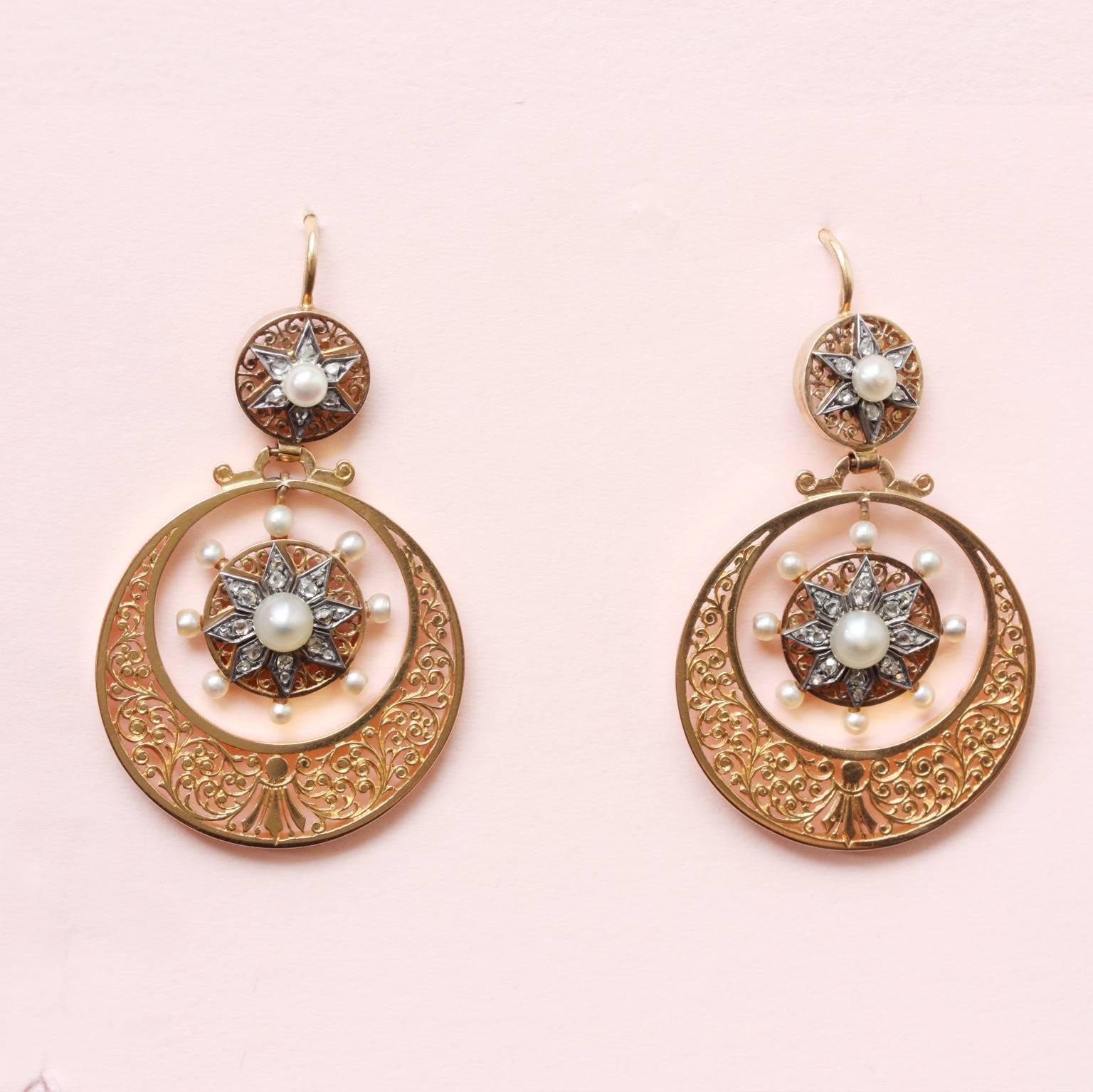 A pair of 18 carat gold circle earrings with a hand engraved foliage decoration, inside a drop with silver stars set with rose cut diamonds  and pearls, with similar tops, France, Savoy, 19th century.

weight: 12 grams
length: 4.5 cm