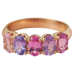 An 18k gold and 5 stone pink and purple sapphire band ring