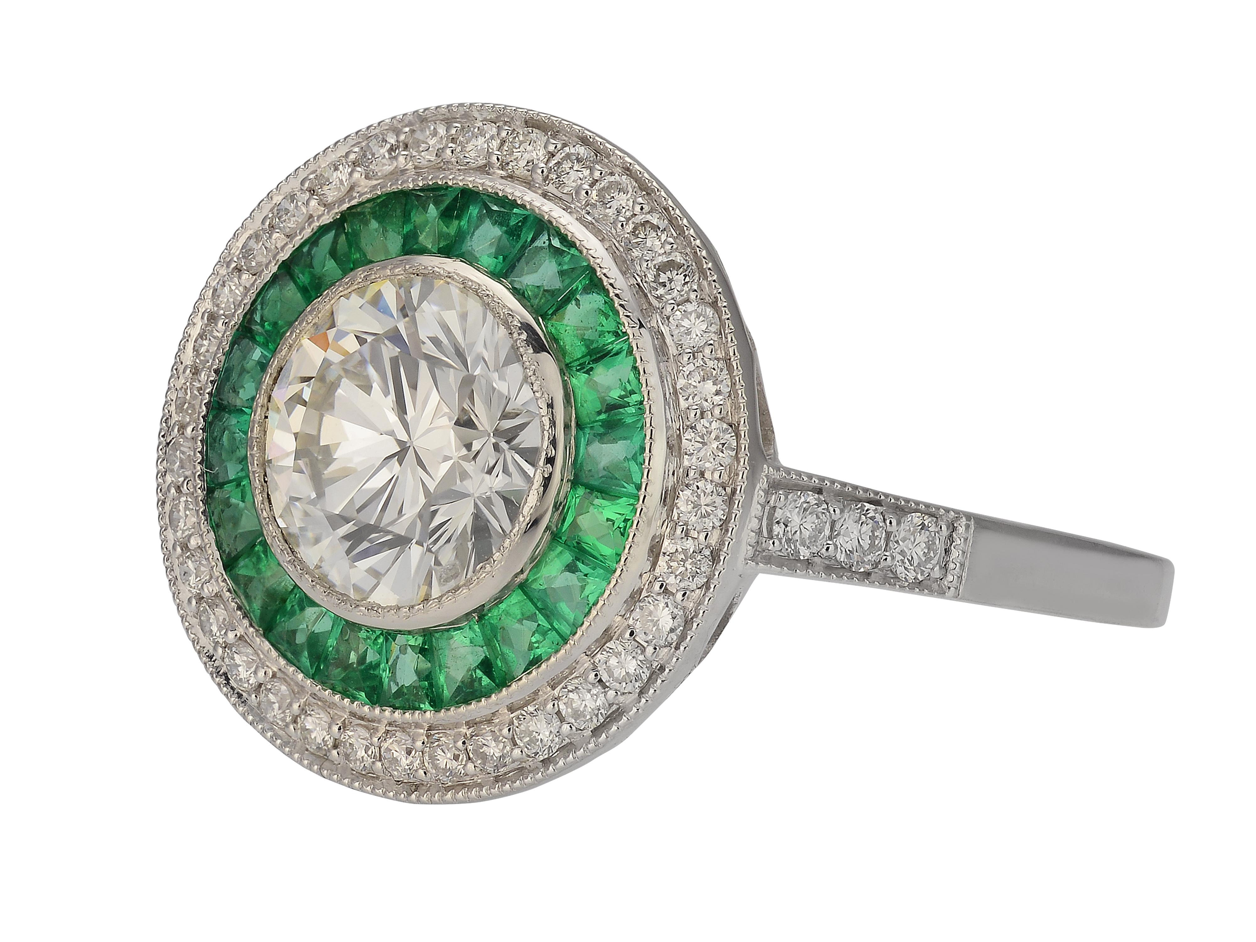 Vintage Inspired Platinum Art Deco Ring Featuring A Bezel Set 1.34 Carat Round Diamond GIA Graded as SI2 Clarity & J Color. It Is Surrounded By 20 Caliber Cut Emeralds Totaling 0.47 Carats, 40 VS Clarity & G Color Diamonds Totaling 0.29 Carats, & A