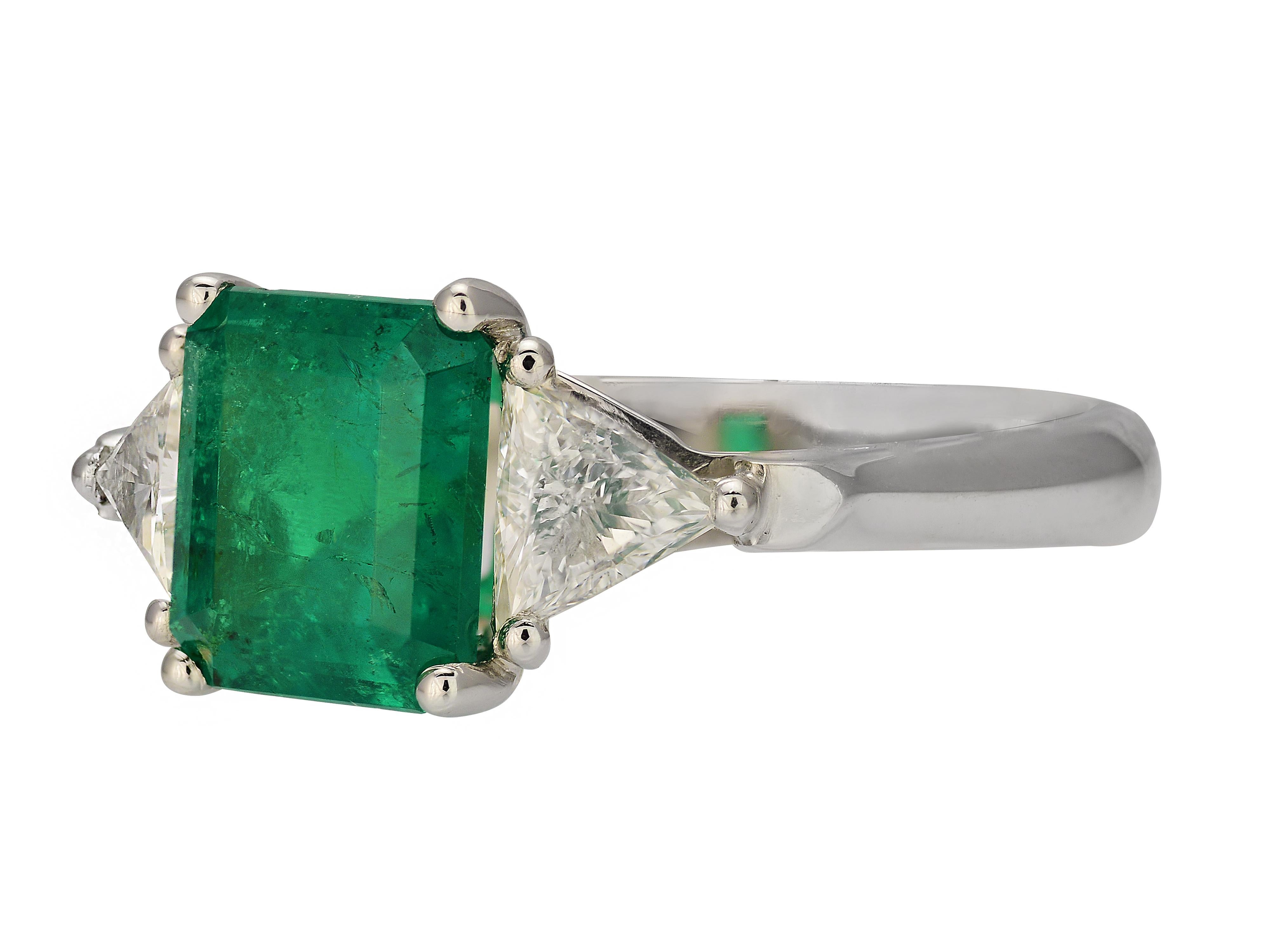 Platinum Three Stone Cocktail Ring Featuring A 1.95 Carat Prong Set Square Cut Cushion Emerald. The Center Stone Is Accented By Two Trilliant Cut Diamonds Of VS Clarity & G Color Totaling 0.46 Carats. Hidden Hearts In Gallery. Finger Size 6;