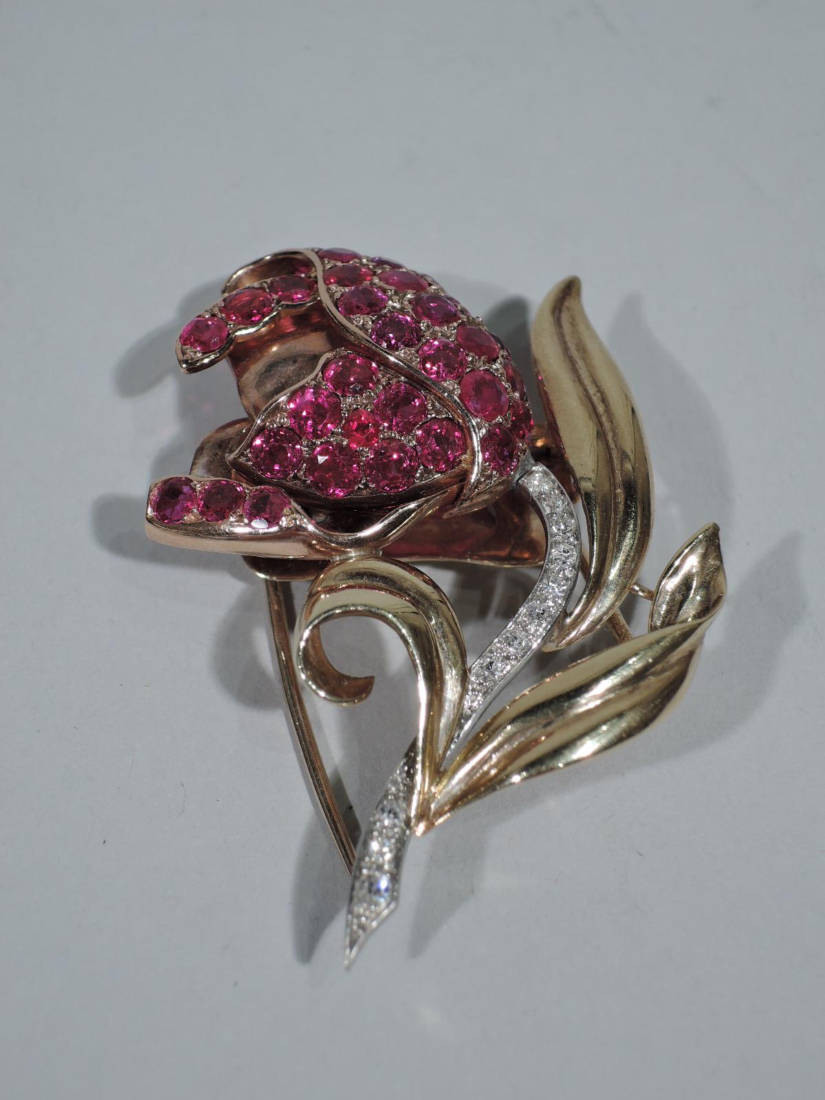 Beautiful 14k gold flower brooch comprising petals inset with 33 rubies (approx. 3 carats) on white-gold stem encrusted with pave diamonds. The flower is framed by 3 scrolled yellow gold leaves. United States, ca 1940s.