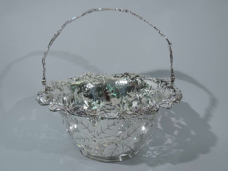 Sterling silver basket in Blackberry pattern. Made by Tiffany & Co. in New York, ca. 1905. Curved and open sides with molded berries and leaves on interior. Rim is everted with applied scrolls and berries. Same to swing handle. Rests on reeded foot