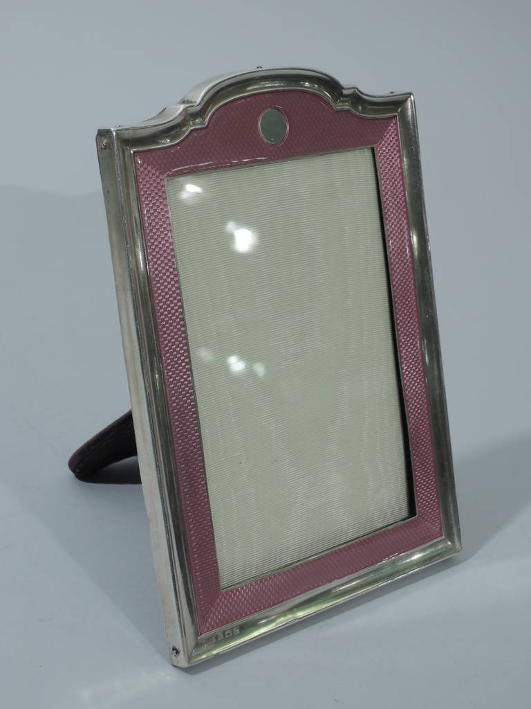 George VI sterling silver and pink enamel picture frame. Made by Henry Matthews in Birmingham in 1942. Rectangular window bordered by engine-turned wave ornament in pink enamel, which in turn is set in concave silver frame. Top is scalloped with
