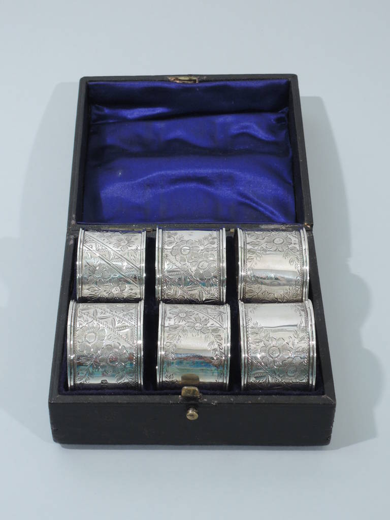 Set of 6 Victorian Aesthetic sterling silver napkin rings. Made by William Richard Corke in London, 1897-99. Each: engraved and styled flowers and geometric ornament. Vacant cartouche. Molded rims. Hallmarked. Excellent condition. 

Dimensions: H