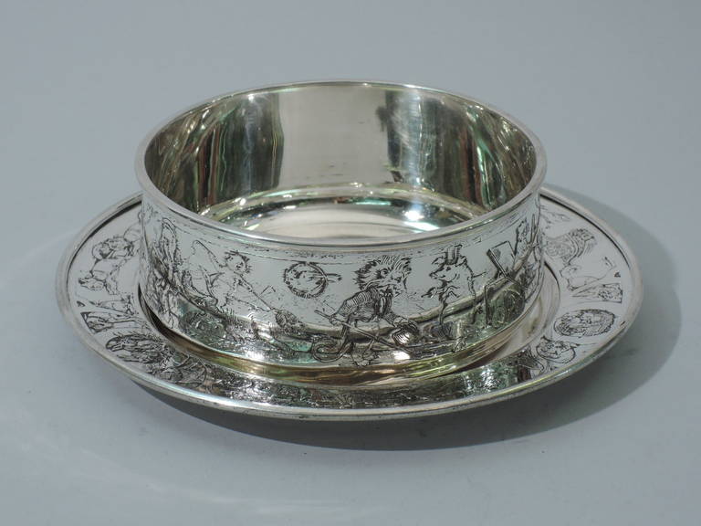 Sterling silver cereal bowl on stand with circus motif. Made by William B. Kerr in Newwark, ca. 1915. Bowl: Upward tapering sides and molded rim. Stand: Well and molded rim. Both: acid etched processions of dancing pigs and porcupines, harnessed