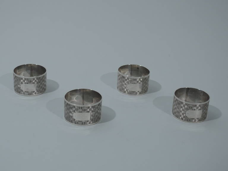 Set of 4 Edwardian sterling silver napkin rings. Made by Charles Westwood & Son in Birmingham in 1906. Raised basket-weave with “tied” label cartouche (vacant). Plain rims. Hallmarked. Excellent condition with nice patina. 

Dimensions: H 1 x D 1