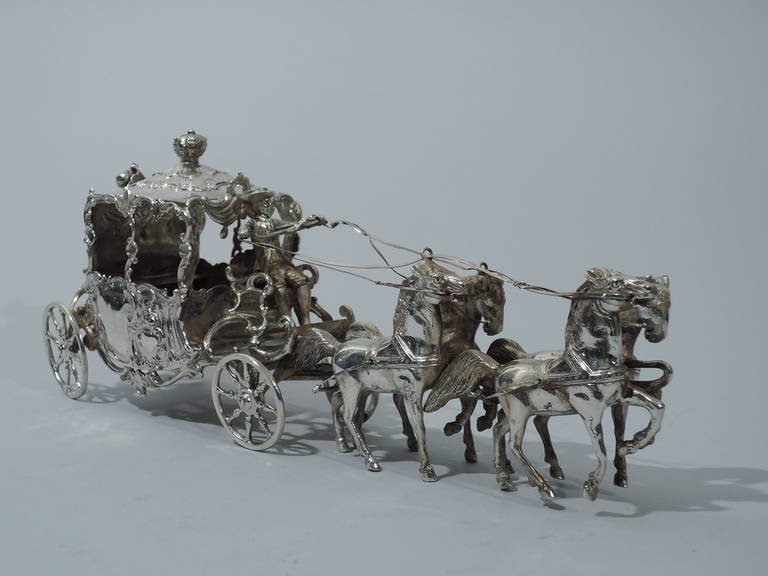 German 800 silver coach-and-four, ca. 1900. Four horses are harnessed to a sumptuous coach. The coach has scrolled-cartouche windows and repousse armorials on doors. Roof is hinged with crown finial. The coachman wears culottes and tricorn hat. In