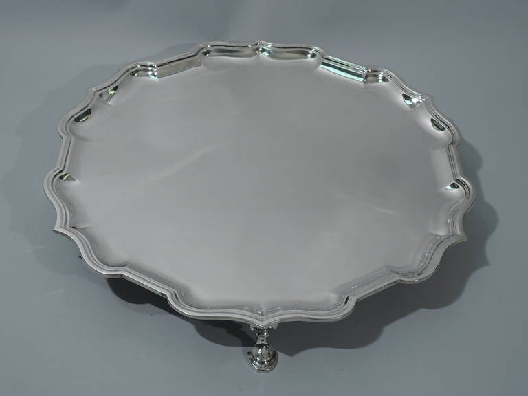 George V sterling silver salver. Made by Charles Stuart Harris in London in 1926 for Tiffany & Co. in England. Curvilinear and molded rim with ogee scalloping. Rests on 4 hoof supports. Hallmark and retailer’s mark “Tiffany & Co.
