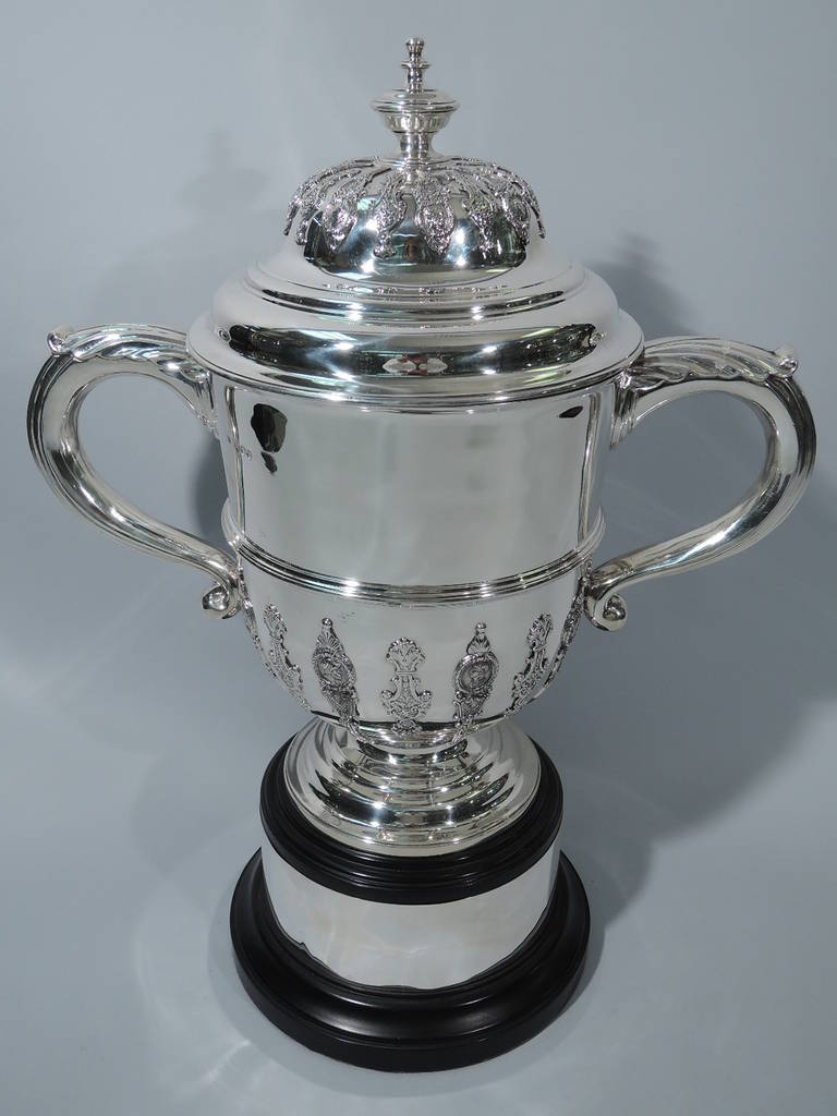 Large Victorian sterling silver trophy cup. Made by Charles Stuart Harris in London, 1891-92. Urn body on stepped foot, capped scroll handles, and flared rim. Vertical strapwork with Classical medallion portraits applied to bottom half. Same applied