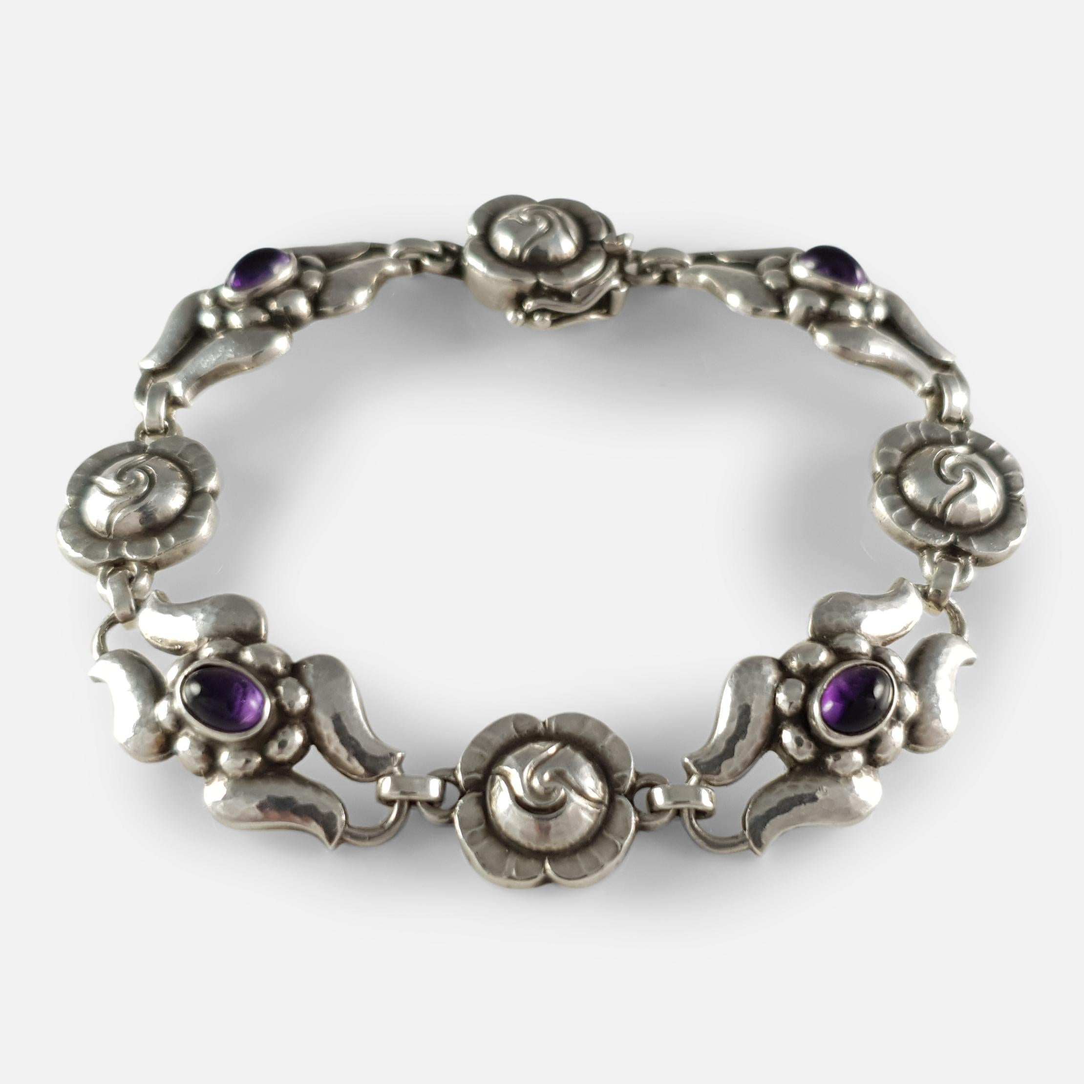 A silver amethyst bracelet, #18, by Georg Jensen, circa 1933-1944. The bracelet is designed as alternating flower heads and scrolling links set with amethyst cabochons.

The bracelet is stamped with the 