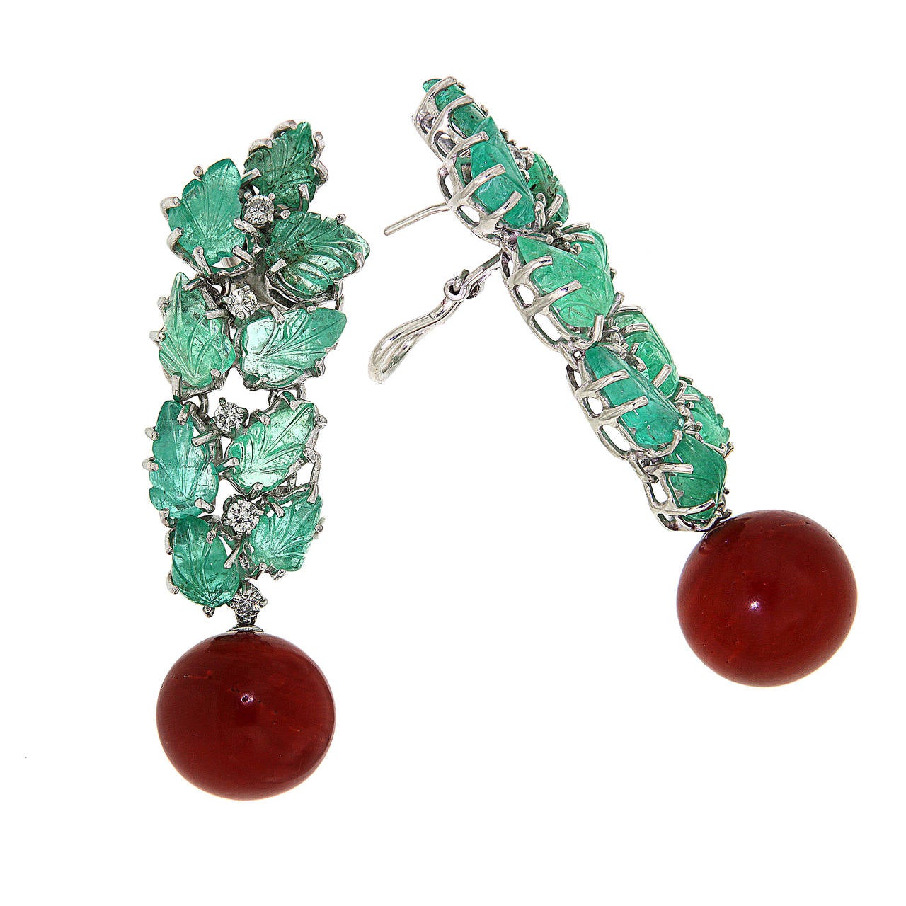Amazing dangle clip-on earrings crafted in 18k white gold with 18 carved natural green emeralds leaf-shape 25.10 ctw, 10 Diamonds 0.80 ctw and rare Mediterranean red coral 62,60 ctw, the size of the ball-shape coral is mm 17 / 0.669