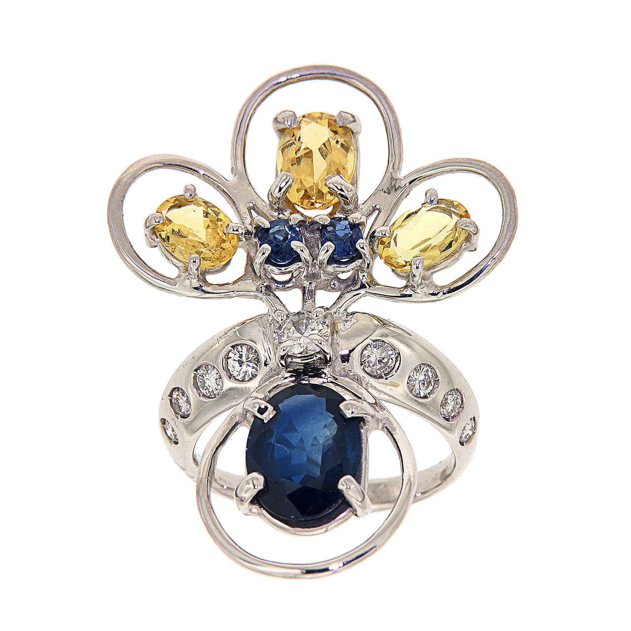 18kt white gold ring inspired by the coloured feathers of a peacock tail.
It displays a beautiful oval Ceylon blue sapphire 2.20 ctw, two blue sapphires 0.25 carat, 
yellow beryls 1.55 carat and diamonds 0.40 carat, finger size is 5.5, it can be