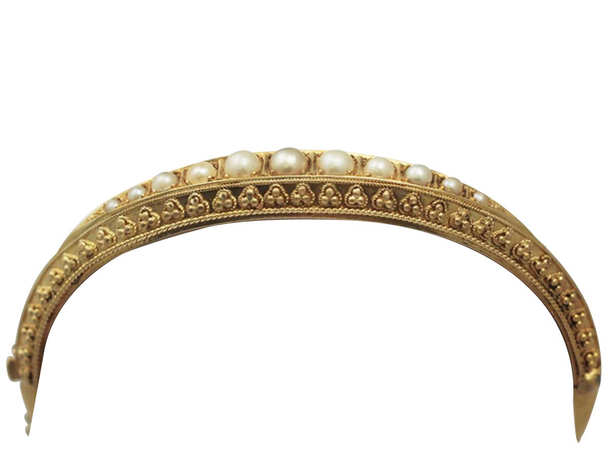 A fine and impressive antique Victorian pearl and 15 karat yellow gold bangle; part of our antique jewelry and estate jewelry collections

This impressive antique gold and pearl bangle has been crafted in 15 karat yellow gold.

The hinged bangle has