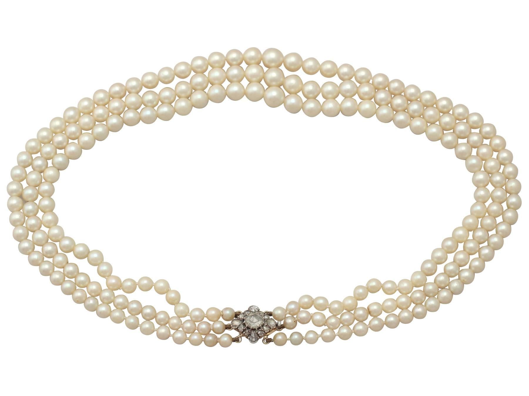 A stunning, fine and impressive three strand vintage (circa 1960) cultured pearl necklace with an antique (circa 1910) 2.11 carat diamond, 18 karat yellow gold and 18 karat white gold set clasp; part of our diverse pearl jewelry collections

This