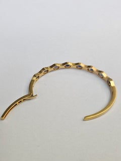 Bracelet manchette moderne orné d'un saphir bleu de Ceylan, monté sur or jaune mat 18 carats