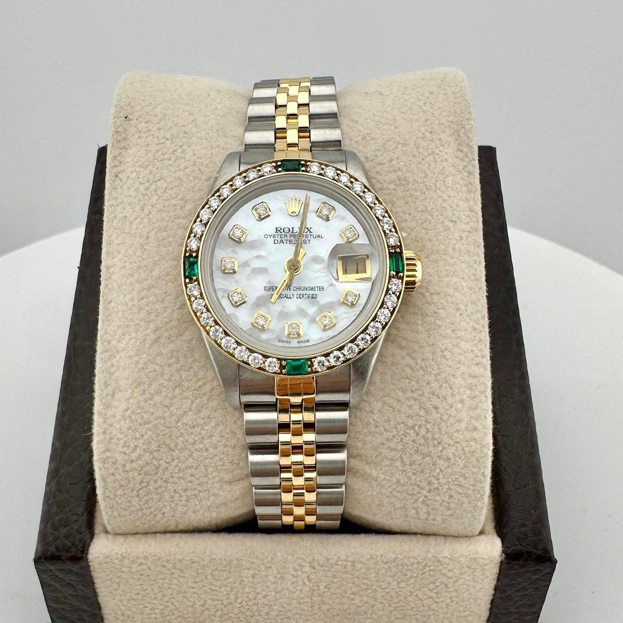 Stil Nummer: 69173

Seriennummer: R828***

Jahr: 1987

Modell: Rolex Damen Datejust

MATERIAL des Gehäuses: Rostfreier Stahl

Band: 18K Gelbgold & Edelstahl

Lünette: Kundenspezifische Diamant- und Smaragd-Lünette

Zifferblatt: Individuelles