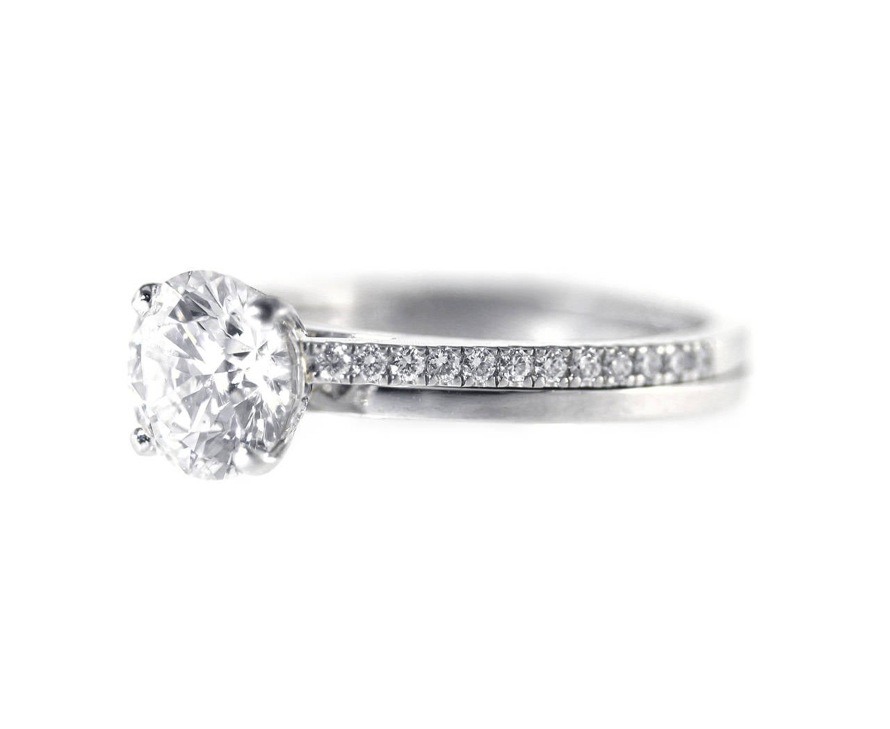 The ideal platinum and diamond engagement ring by DeBeers, set in the center with a round diamond weighing 1.06 carats, flanked by 33 round diamonds weighing approximately 0.15 carat, gross weight 5.0 grams, size 4 3/4, measuring 3/4 by 1/4 by 7/8