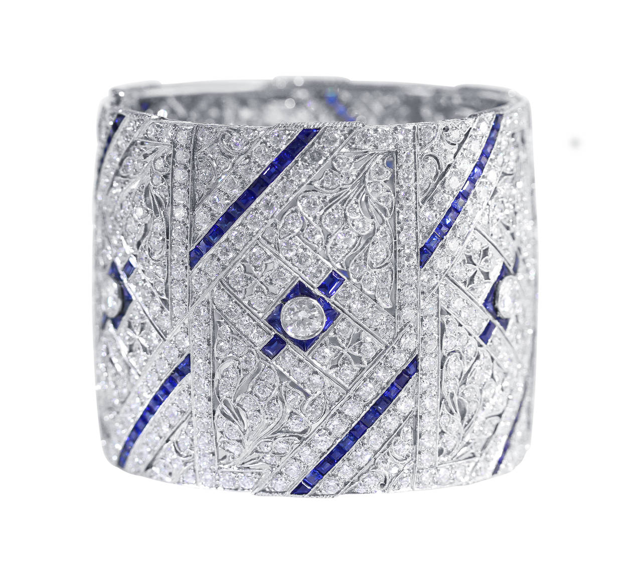 A stunning Art Deco platinum, diamond and sapphire bangle bracelet, the wide bangle of openwork floral and geometric design set in the center with an old European-cut diamond weighing approximately 1.50 carats, further set with 5 old European-cut