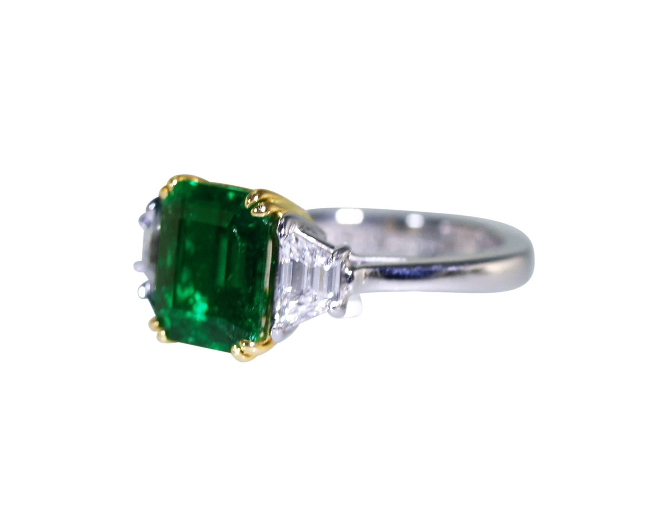 Platinum, 18 karat yellow gold, emerald and diamond ring, set in the center with an emerald-cut emerald weighing 3.33 carats, flanked by 2 trapezoid diamonds weighing 0.89 carat, gross weight 8.6, measuring 3/8 by 7/8 by 1 inch, size 6 1/4, signed