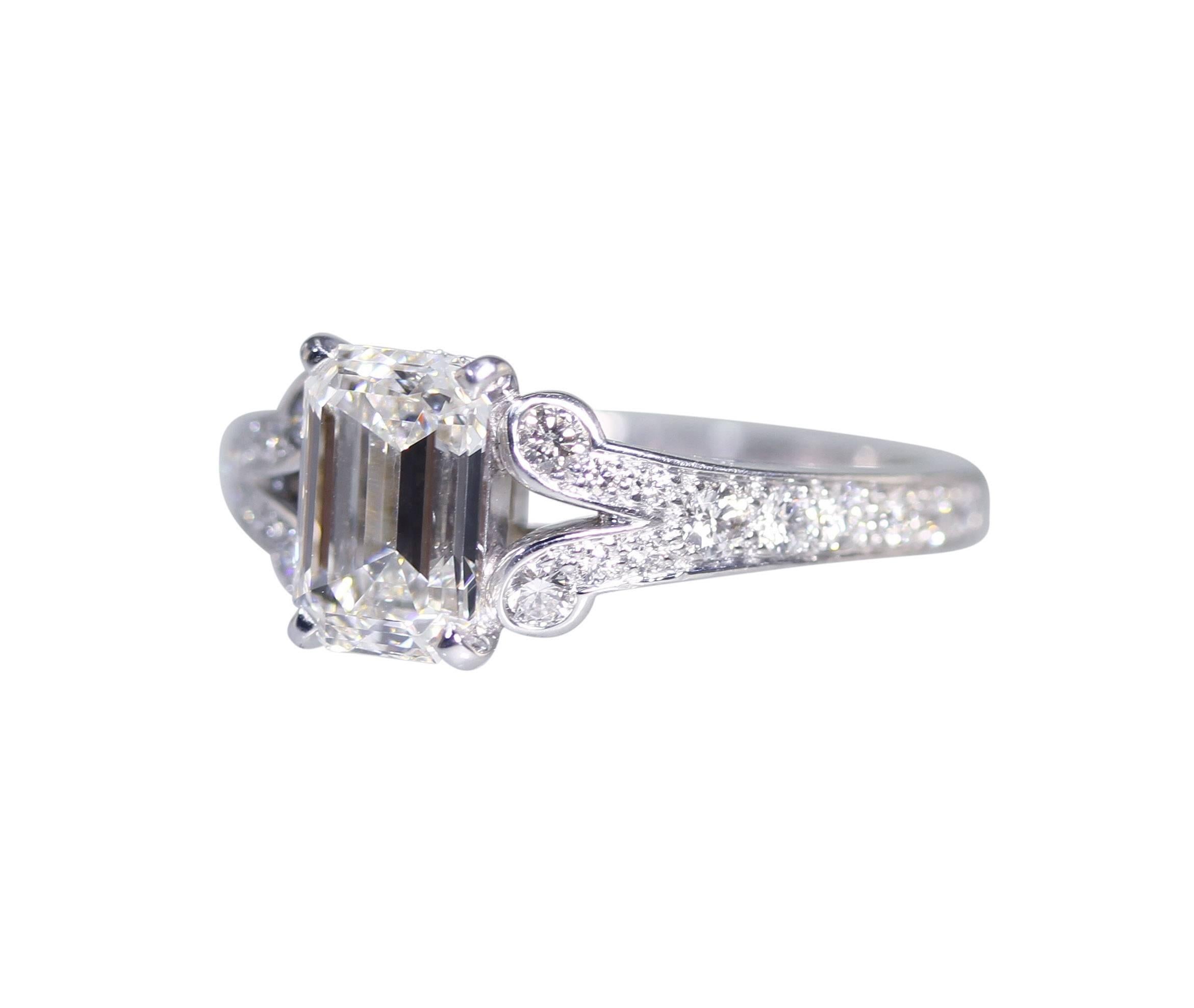 A platinum and diamond ring by Cartier, set in the center with an emerald-cut diamond weighing 1.55 carats, flanked by 24 round diamonds weighing approximately 0.50 carat, gross weight 5.3 grams, measuring 1/4 by 3/4 by 7/8 inch, size 4 with sizing