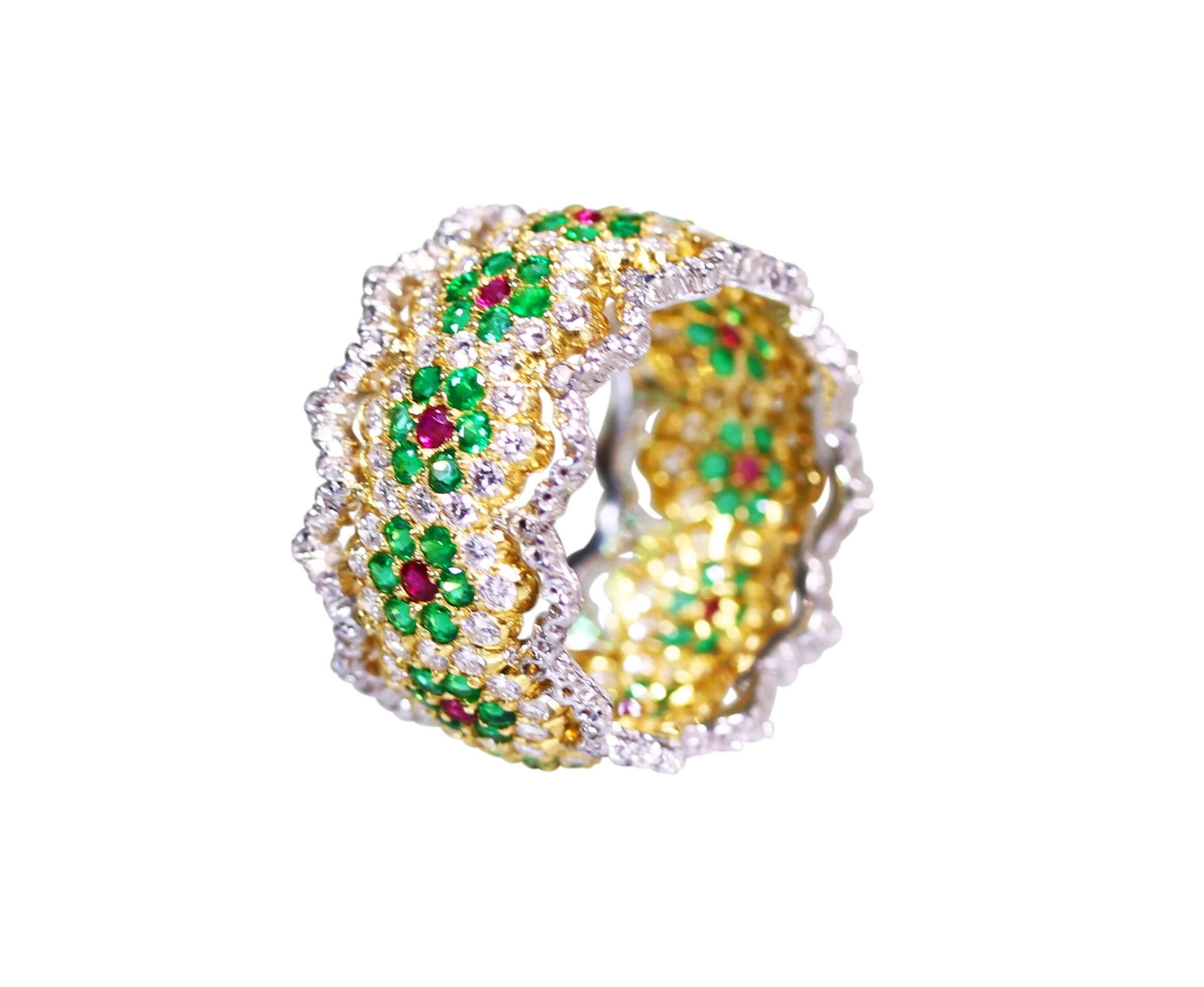 An 18 karat white and yellow gold, ruby, emerald and diamond ring by Buccellati, Italy, the wide band of openwork and floral design, set with 12 round rubies weighing approximately 0.35 carat, 72 round emeralds weighing approximately 1.50 carats,