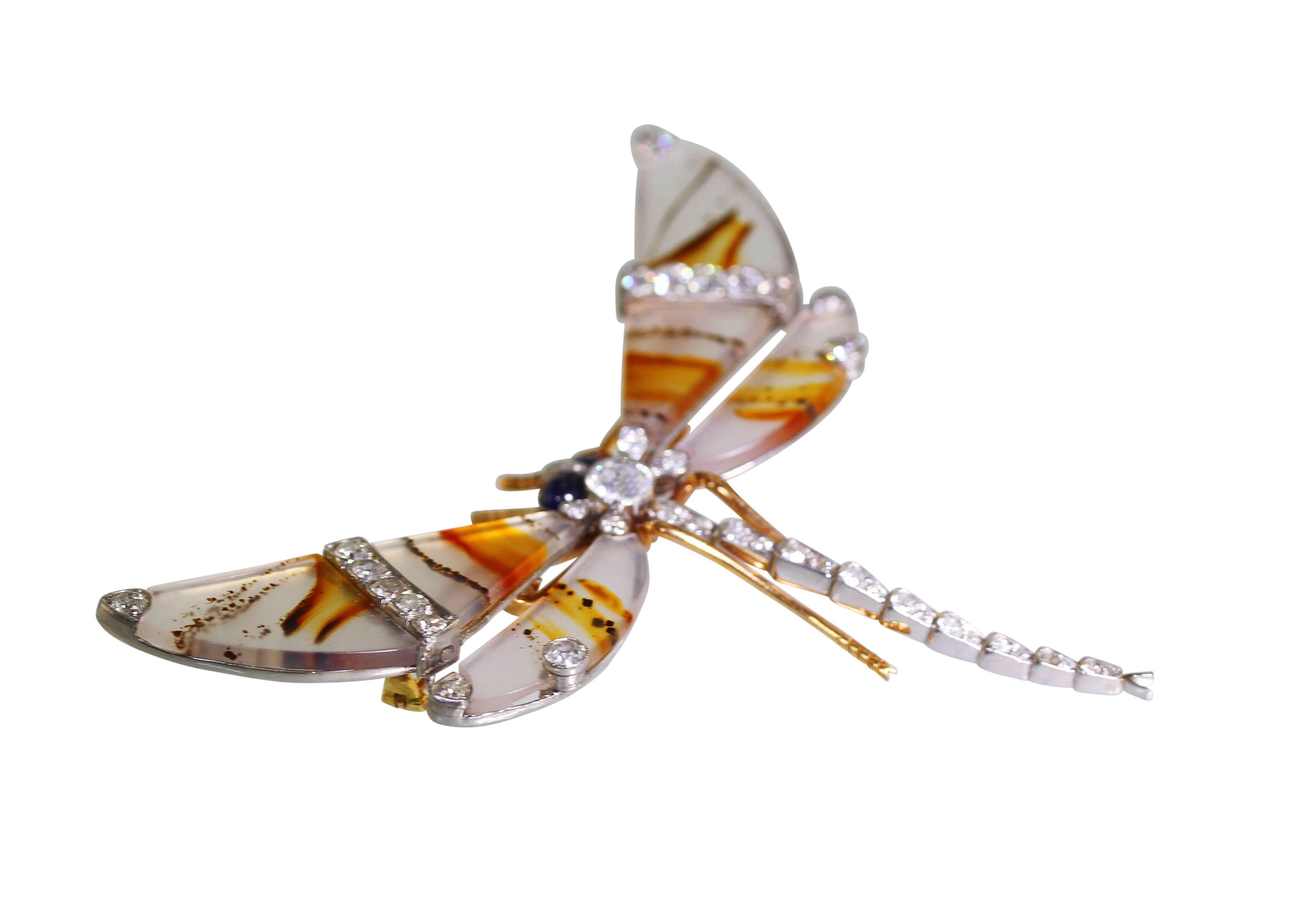 An Edwardian platinum, 18 karat gold, diamond, sapphire and agate brooch, designed as a dragonfly with all four wings made of natural agate design, accented by 45 round diamonds weighing approximately 2.25 carats, further accented by 2 cabochon