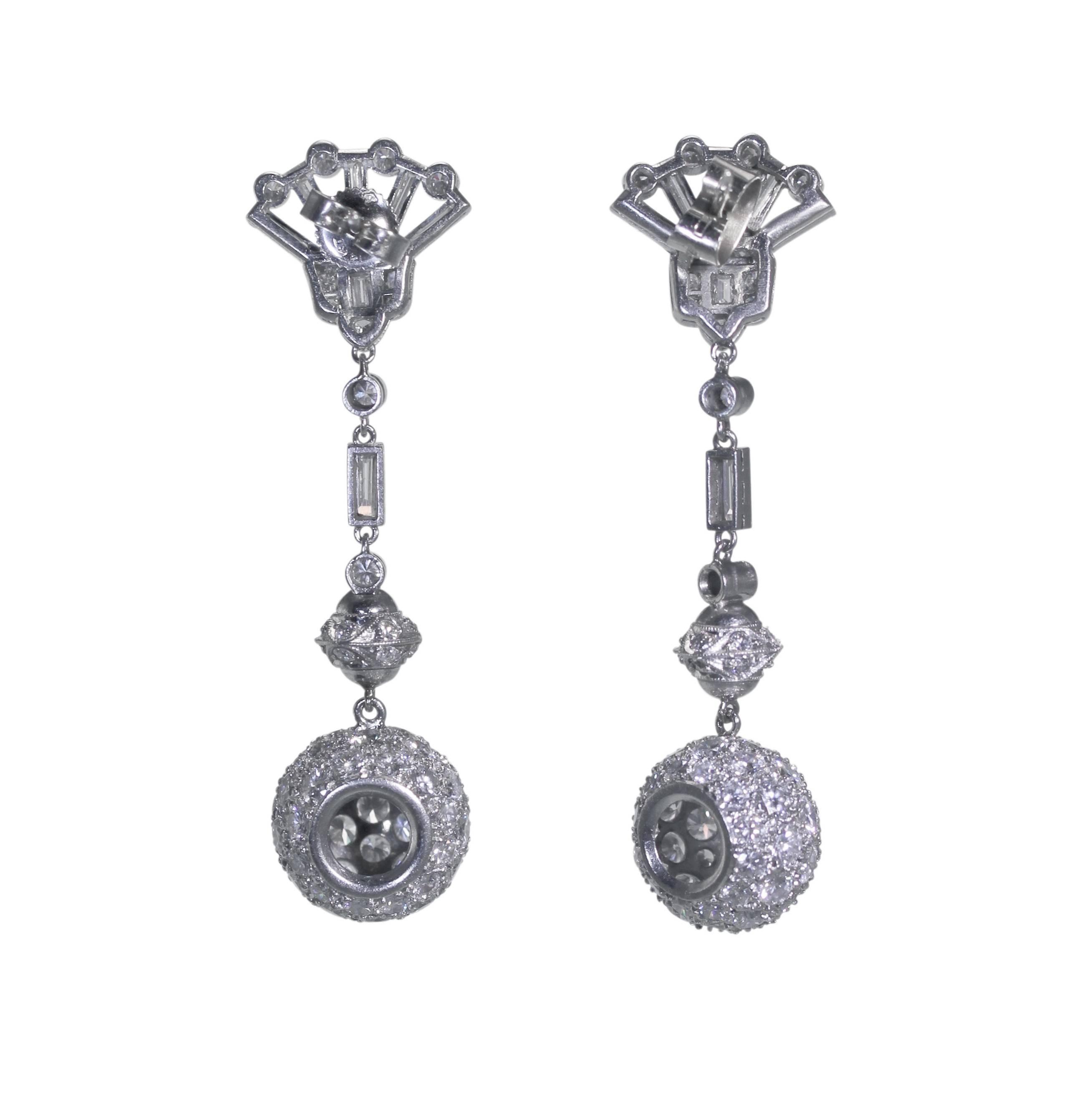 A pair of platinum and diamond pendant earrings, circa 1950, supporting spherical drops surmounted by multiple sections completed by fan-shaped tops, set throughout with 160 round diamonds weighing approximately 4.50 carats, accented by 14 baguette