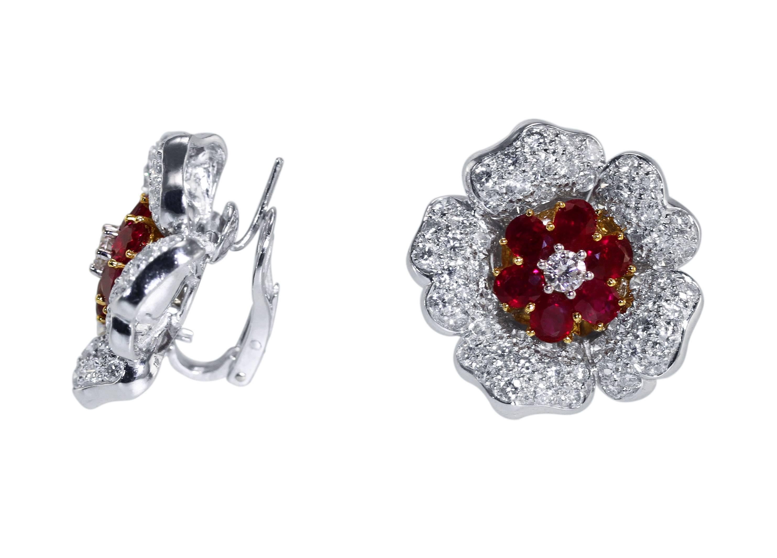A pair of Platinum, 18 karat gold, ruby and diamond earclips, designed as flowerheads set in the center with 10 oval rubies weighing approximately 5.00 carats, further set with 128 round diamonds weighing approximately 6.00 carats, measuring 1 by 1