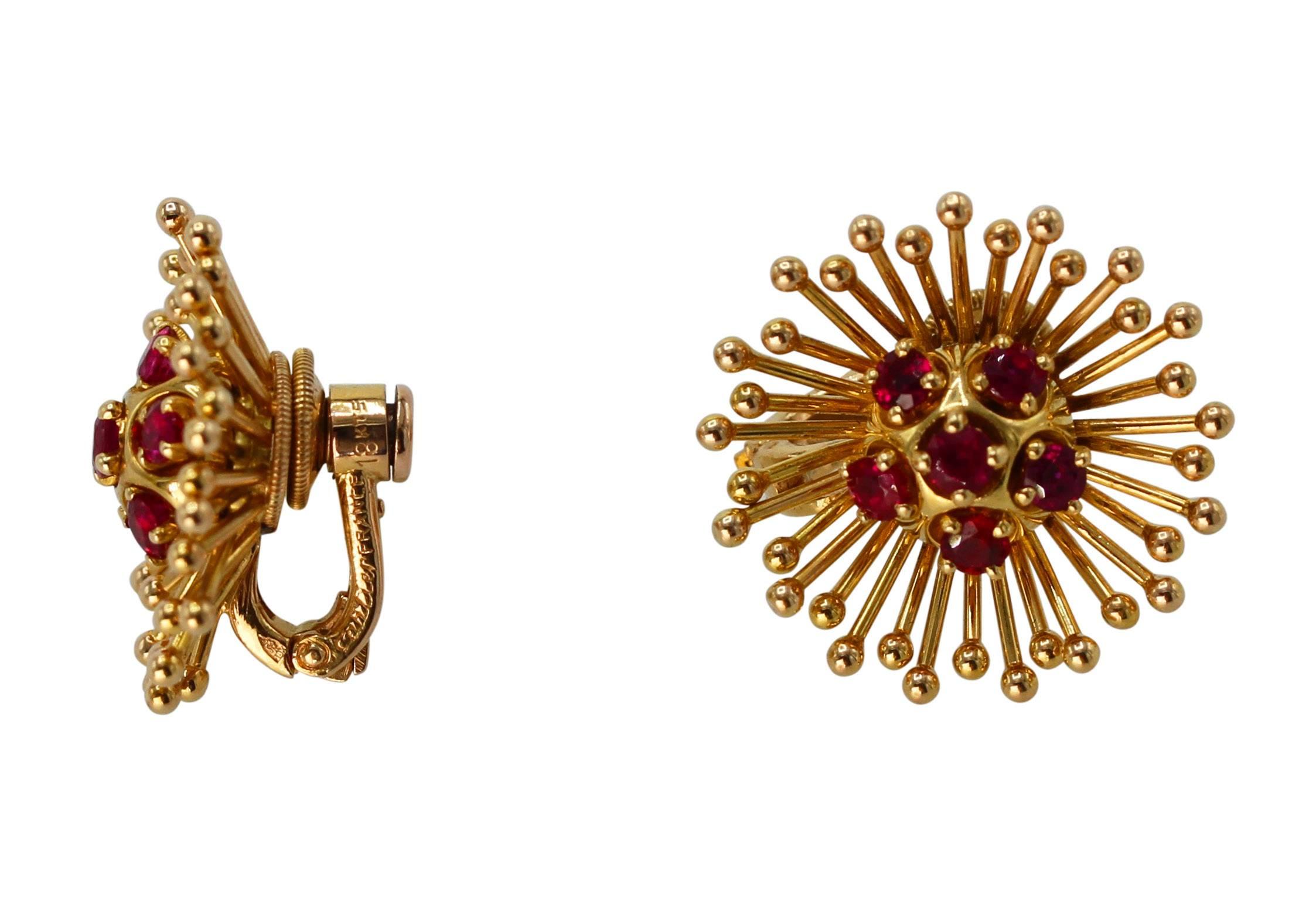 A pair of 18 karat yellow gold and ruby earclips by Cartier, France, circa 1960, designed as flower heads set in the center with 12 round rubies weighing approximately 2.40 carats, with gold tendril petals, gross weight 13.4 grams, measuring 7/8 by
