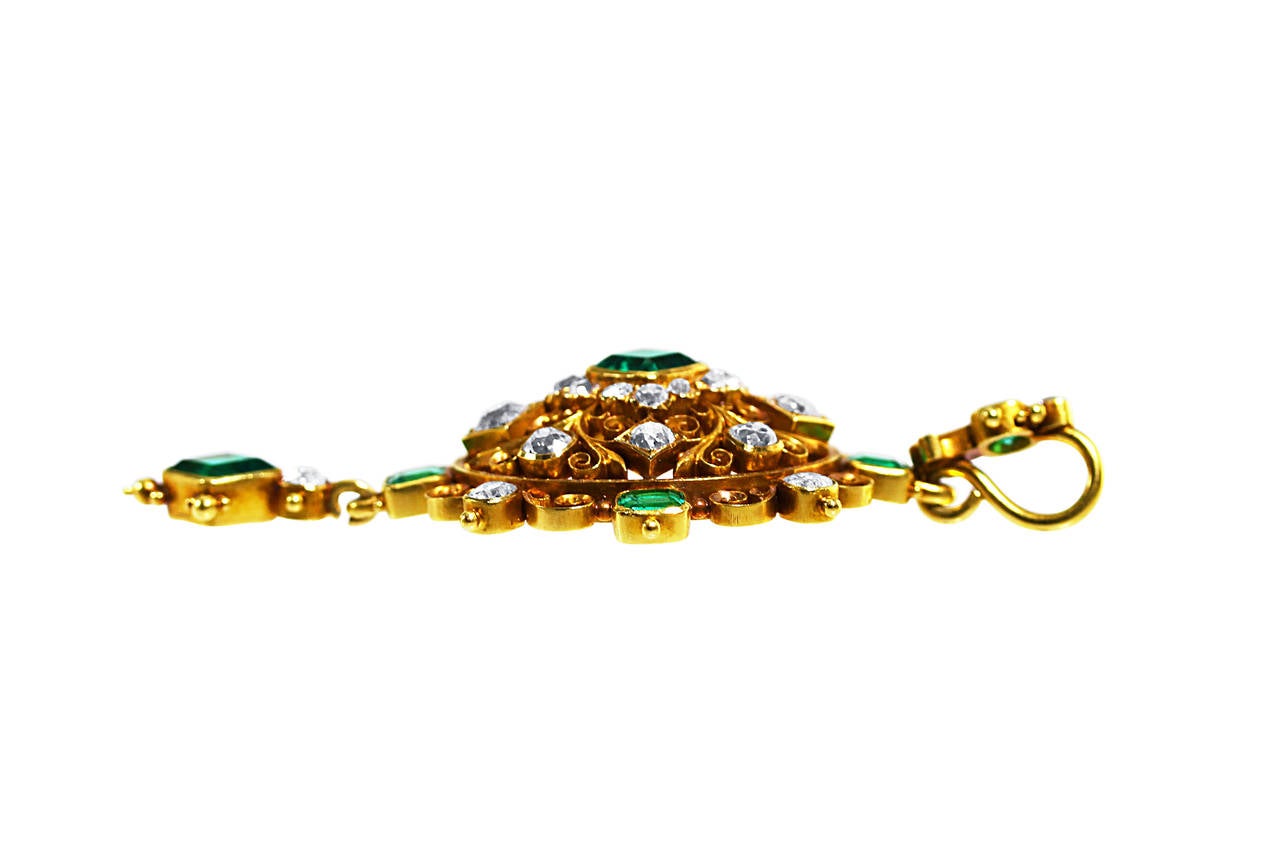 An antique gold, emerald and diamond pendant, circa 1850, designed as an openwork oval plaque of bombe form supporting an articulated pendant, set throughout with 7 step-cut emeralds weighing approximately 3.60 carats, further set with 26 old