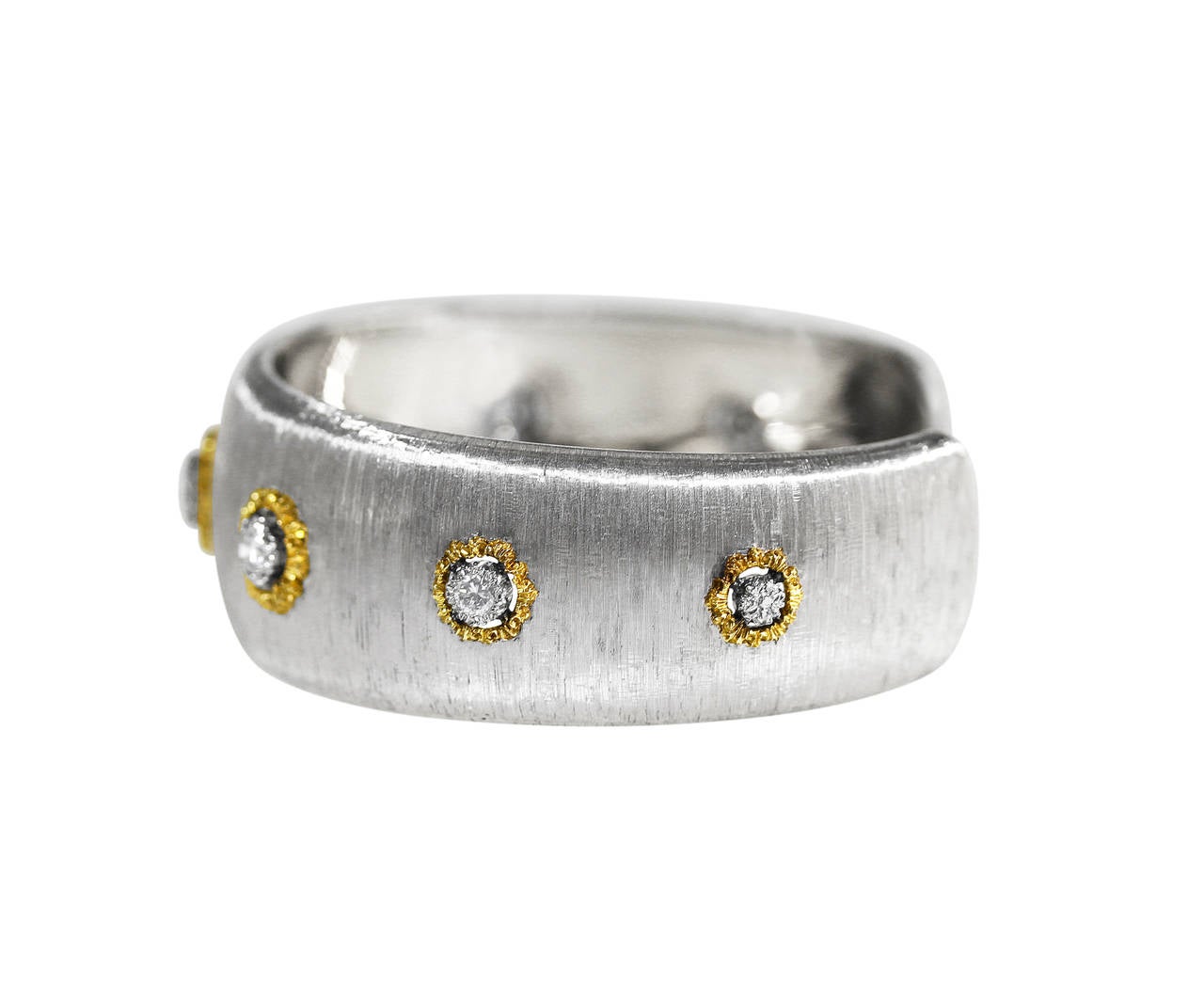 An 18 karat white and yellow gold and diamond bangle bracelet by Buccellati, Italy, the slightly tapered band of brushed white gold accented by graduated yellow gold plaques set with 5 round diamonds weighing approximately 1.00 carat, gross weight