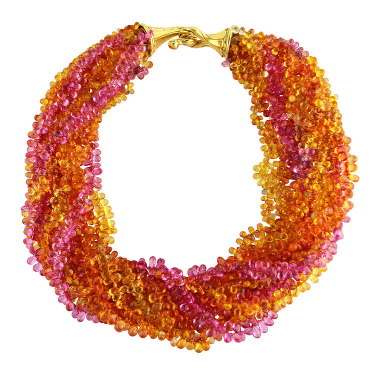 Absolutely stunningly vibrant colors in this 18 karat yellow gold and multi-colored sapphire torsade necklace by Andrew Clunn, the twelve strand necklace composed of numerous yellow, orange and pink faceted briolette sapphires weighing approximately