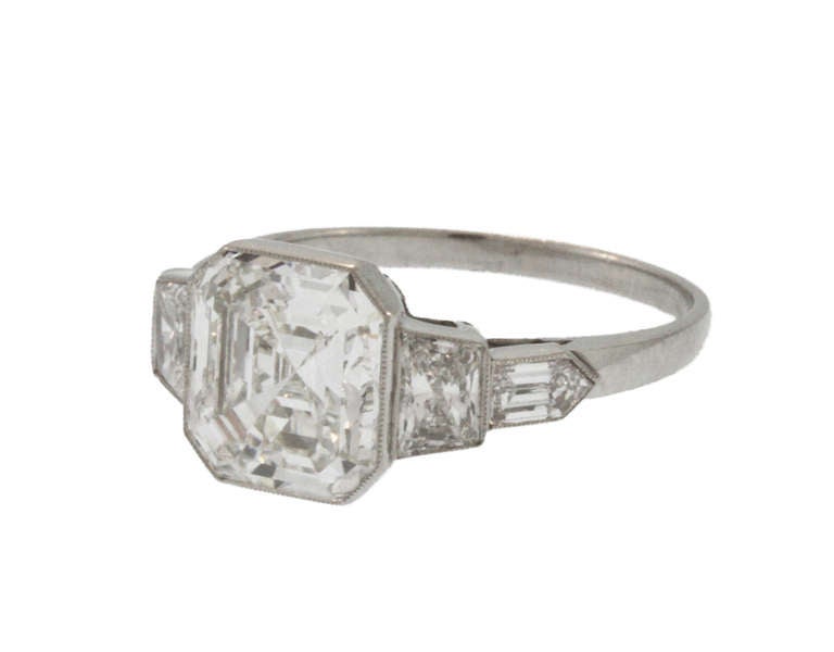 Platinum and diamond ring set in the center with an asher-cut (square emerald-cut) diamond weighing 3.00 carats, flanked by 2 trapeze-cut and 2 bullet-shaped diamonds weighing approximately 0.75 carat, gross weight 3.8 grams, size 5 1/2, measuring